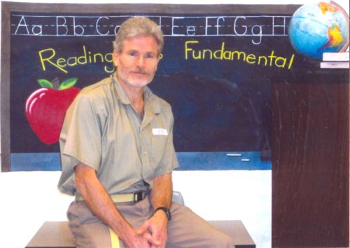 Photo of Bill Dunne in khaki prison uniform in a classroom