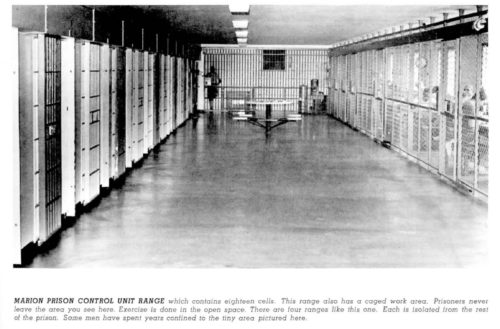Photo of empty prison corridor with barred cells on all sides