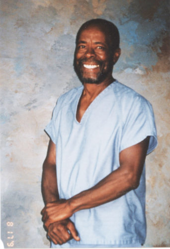Smiling dark skinned man with beard and broad smile in prison uniform