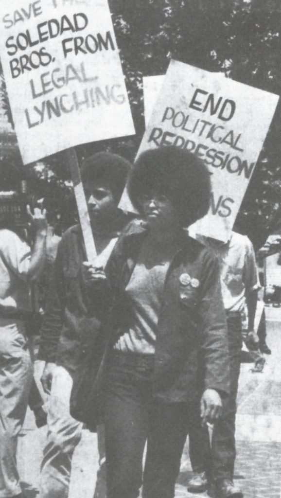 Picture of Angela Davis in a picket line holding a sign reading save the Soledad Brothers from Legal Lynching